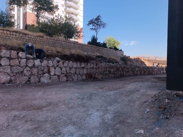 Mardin inşaat alanında Martaç Hafriyat ekipleri tarafından taş duvar örme işlemi gerçekleştirilirken çevrede kum ve mıcır kullanılıyor.