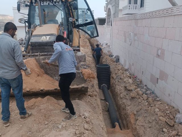 Martaç Hafriyat işçileri, Mardin’de altyapı için kazılan hendekte kum ve mıcır dolgu yaparak drenaj borusu döşüyor.