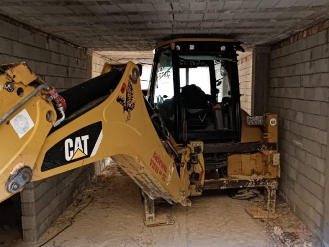 Kapalı alanda Martaç Hafriyat’a ait kazıcı makine, Mardin’de taş duvar çevresinde zemin hazırlığı ve hafriyat çalışması yapıyor.