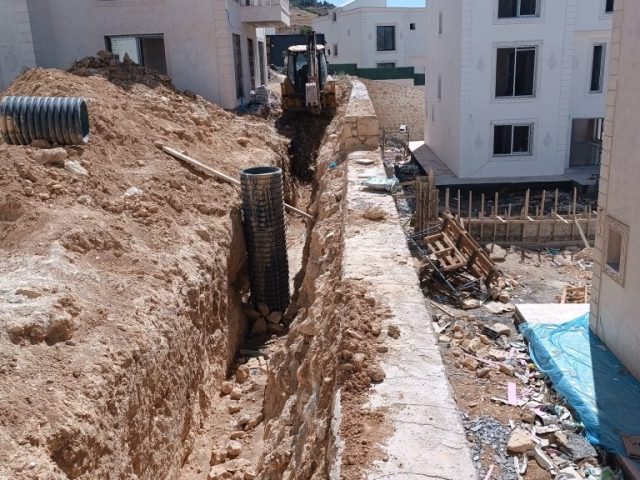 Martaç hafriyat ekibi Mardin'de kazı çalışması yaparken, taş duvar yanındaki derin hendeği kum ve mıcırla doldurmak için hazırlık yapıyor.