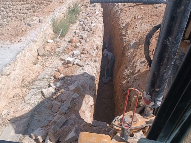 Mardin'de Martaç hafriyat hizmeti kapsamında taş duvarın yanında geniş bir hendek kazılıyor, kum ve mıcır dolgusu için zemin hazırlanıyor.