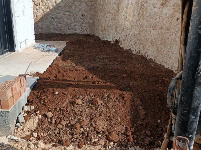 Martaç hafriyat Mardin ekibi taş duvar önünde kum ve mıcır ile zemin düzenleme yapıyor, hafriyat sonrası alan temizleniyor.