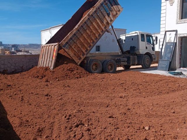 Martaç hafriyat kamyonu mardin’de taş duvar yanında kum ve mıcır boşaltıyor, inşaat çalışmaları için.